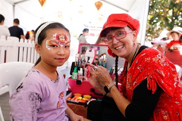Close up of face painter and young girl with painted face