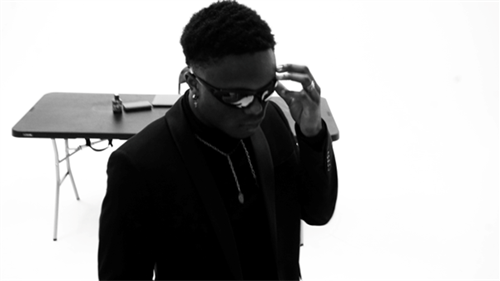 Artist Nakarel in a black and white photo posing in front of a table