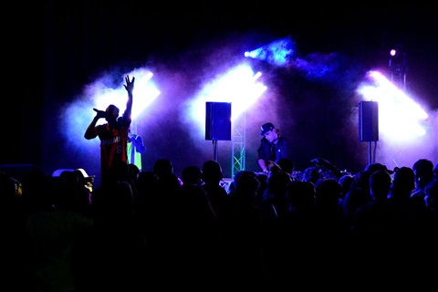 Dance Party at with an MC and DJ on stage sihouetted by lights