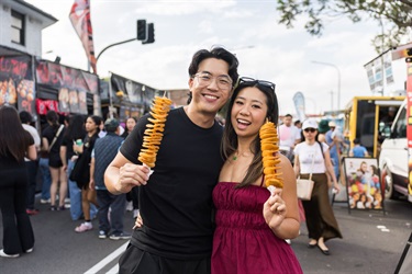 Couple holding chips on a stick at Cabramatta Moon Festival 2025 photo by Anna Kucera.