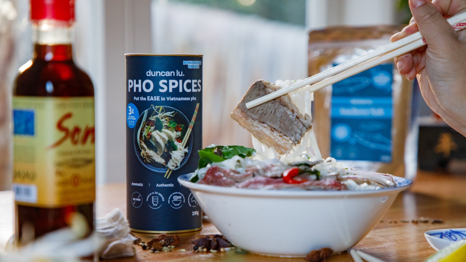 Chopsticks holding piece of beef from Pho dish by Duncan Lu.