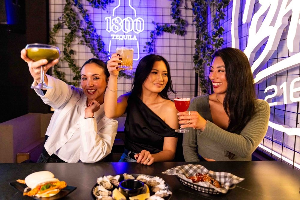 3 women drinking cocktails at a bar