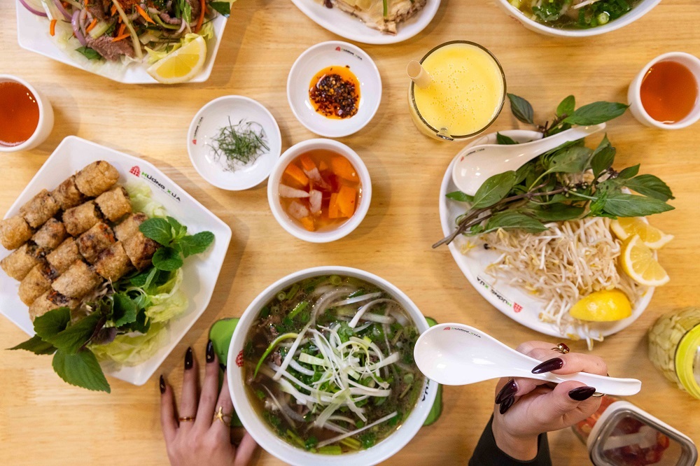 Huong Xua food spread with hands holding spoon.