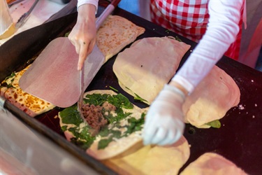 A meat and spinach dish being prepared by a food vendor