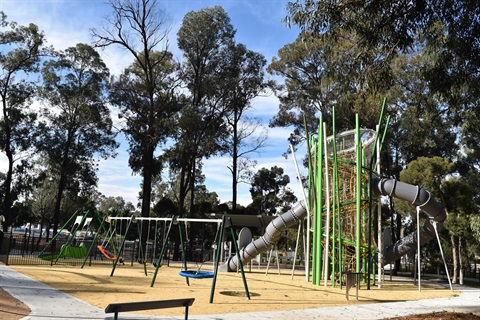 Swings, Climbing tower and slide with trees in the background
